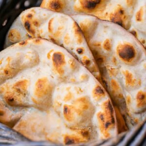 Naan Basket with an assortment of fresh, soft naans including plain, butter, garlic, and cheese naan – served hot in a woven basket.
